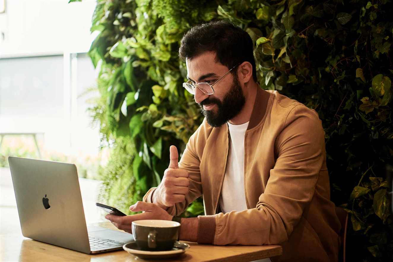 Image of a man showing thumbs up while looking at his laptop