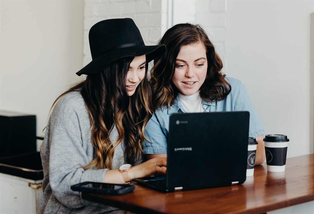 Image of a girl helping another girl on laptop